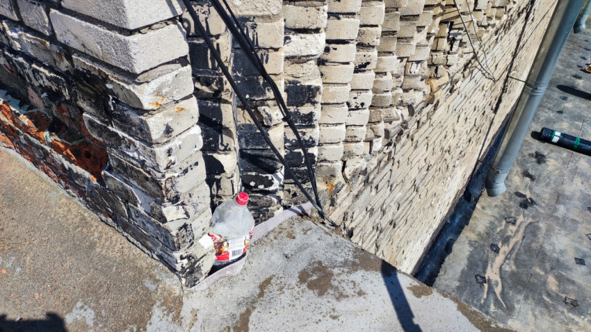 Кирпичная стена здания с повреждениями и кабелями