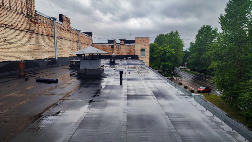 Плоская крыша здания после дождя с рулонным покрытием