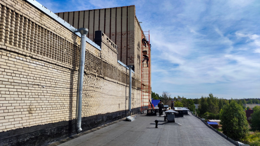 Рабочие на крыше здания с лесами и оборудованием