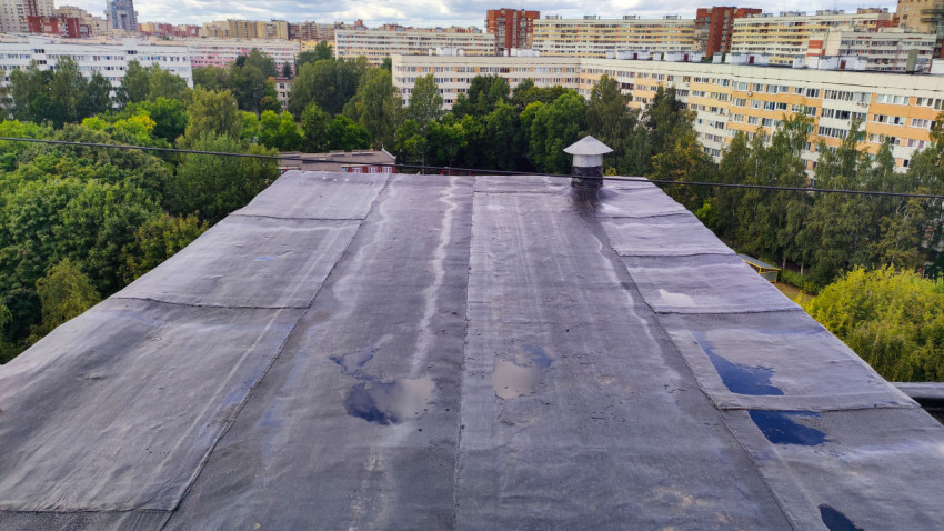 Плоская крыша жилого дома с лужами после дождя