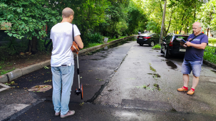 Осмотр дворовой дороги с люком и зелеными насаждениями