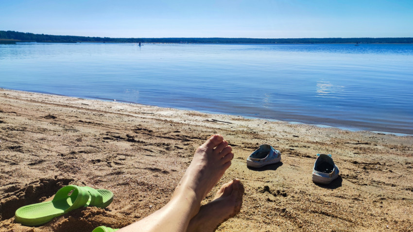 Песчаный пляж с ногами человека на переднем плане