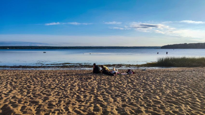 Люди на песчаном пляже у водоема