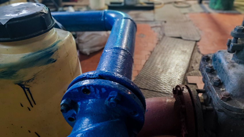 Изогнутый участок трубопровода возле ёмкости в техническом помещении