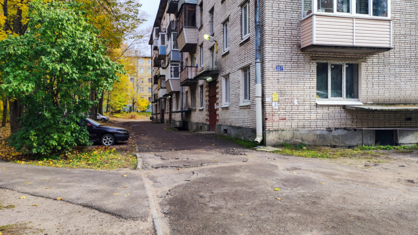 Подъезд жилого дома с асфальтовой дорожкой и парковкой