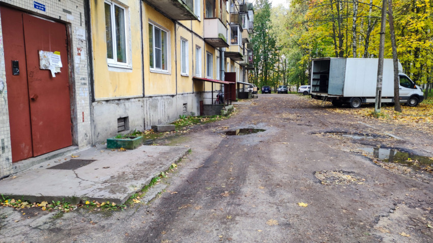 Вход в подъезд панельного дома с повреждённым асфальтом