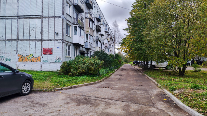 Панельный жилой дом с балконами и деревьями вдоль дороги