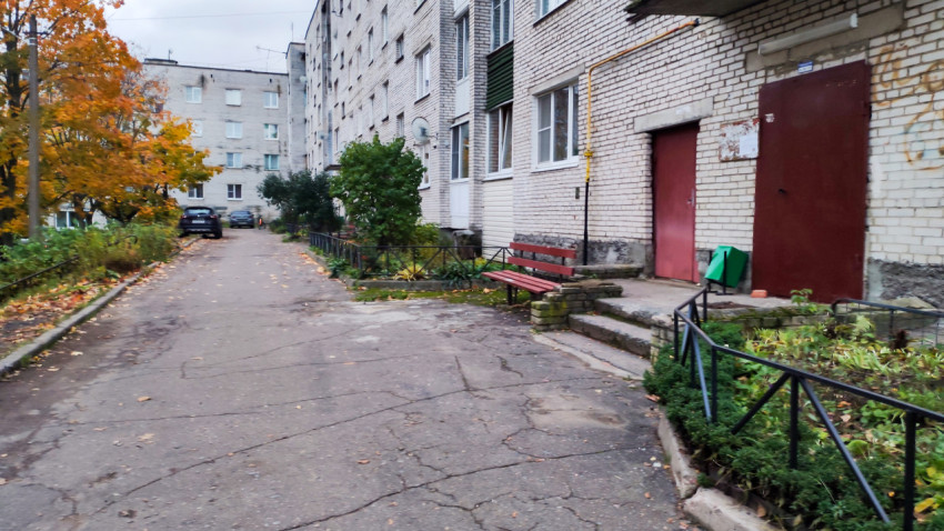 Подъезд жилого дома с лавочкой и клумбой