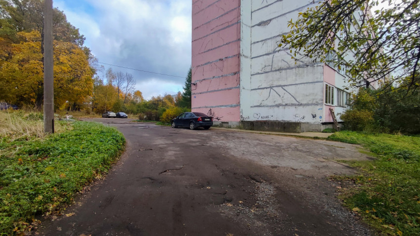 Торец панельного дома и дворовая дорога с припаркованными машинами