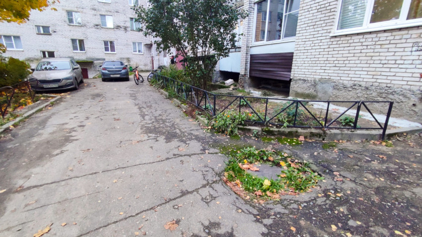 Асфальтированный двор с клумбой и припаркованными автомобилями