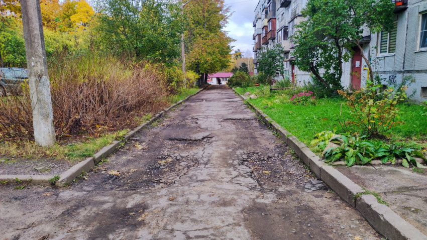 Повреждённая асфальтовая дорога у жилого дома