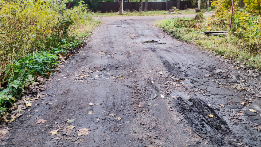 Разбитое покрытие грунтовой дороги с ямами и колеями