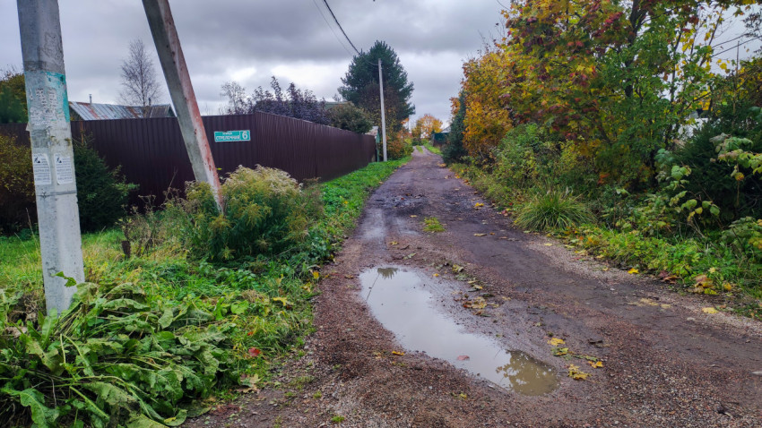 Грунтовая улица с лужами после дождя в частном секторе