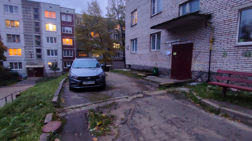 Вечерний двор с автомобилем у кирпичного дома