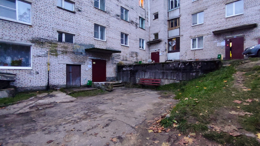 Двор кирпичного жилого дома с подъездами и лавочкой