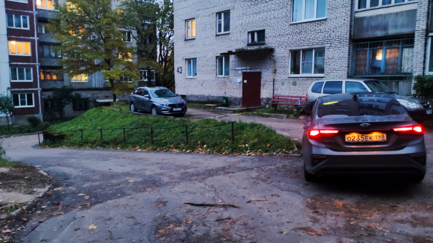 Двор многоэтажного дома с заездом и зелёной клумбой