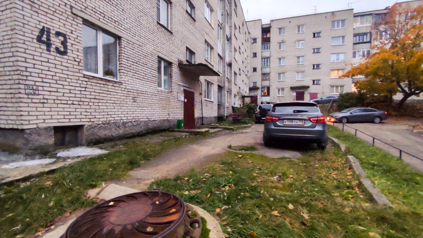 Двор жилого дома с припаркованными автомобилями и номером 43 на фасаде