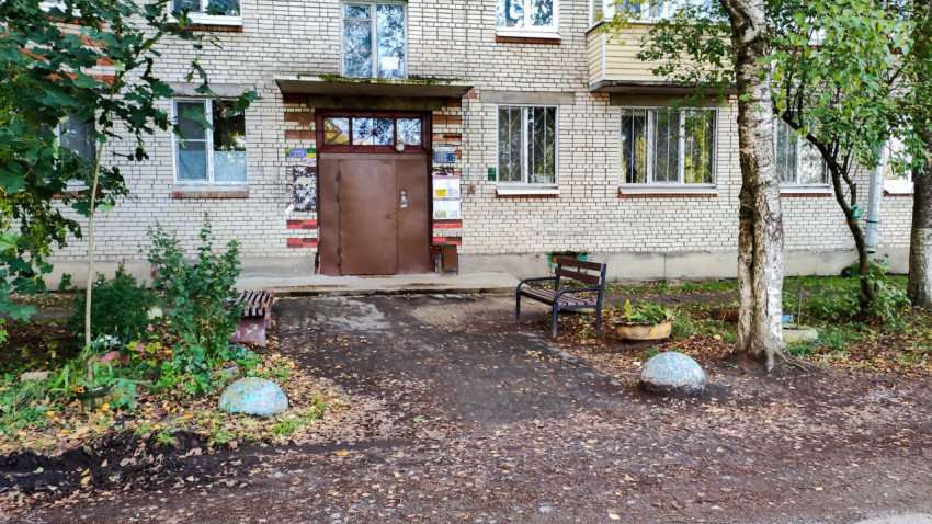 Вход в подъезд жилого дома с лавочкой и зелёными насаждениями