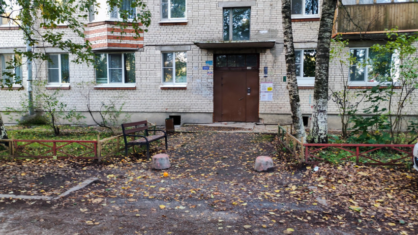 Подъезд жилого дома с лавочкой и декоративным забором