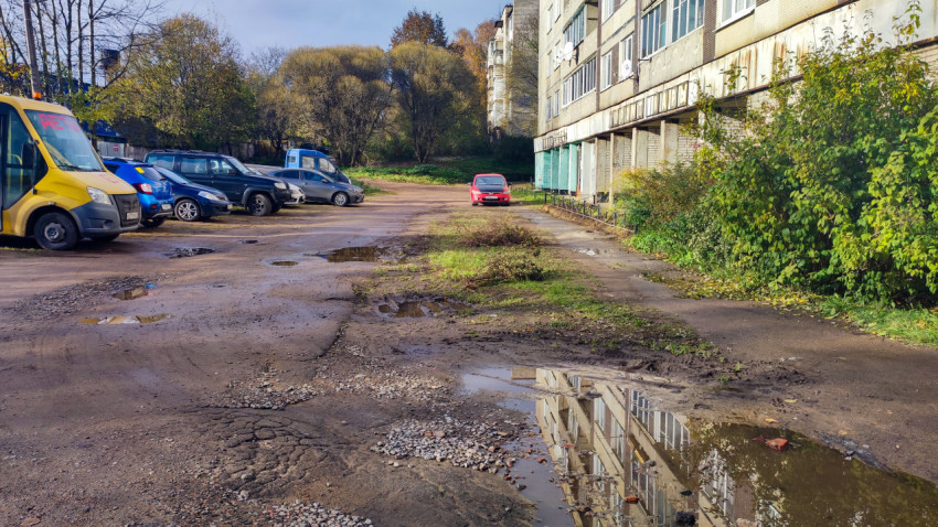 Дворовая парковка с грунтовым покрытием и лужами