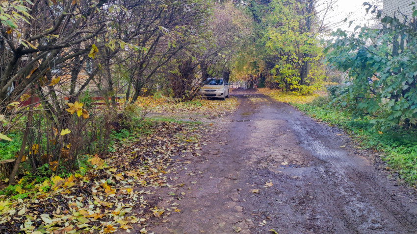 Грунтовая дорога во дворе с припаркованным автомобилем