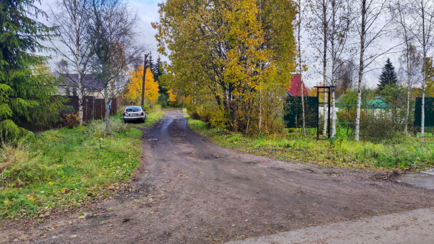 Просёлочная дорога у домов с припаркованным автомобилем осенью