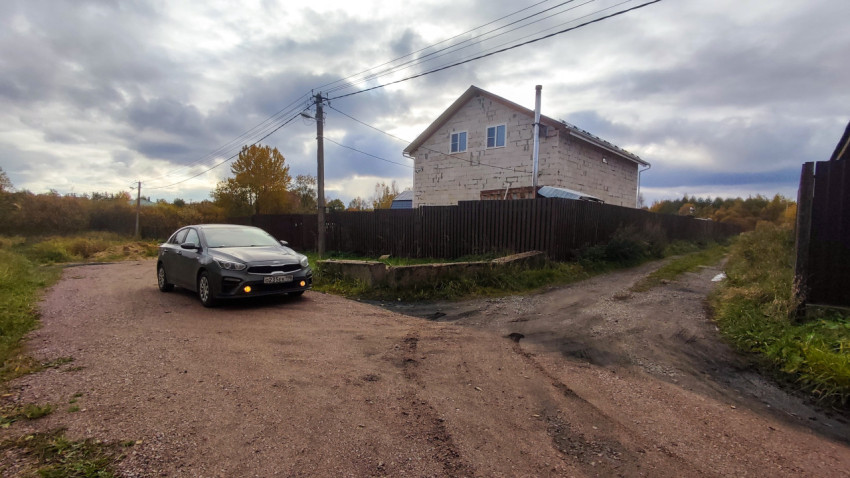 Автомобиль на грунтовой дороге у дома в частном секторе