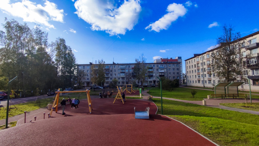 Игровая площадка с качелями и горкой среди жилых домов