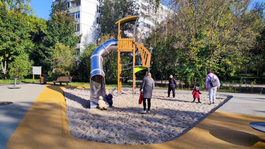 Дети и взрослые на игровой площадке с горкой во дворе