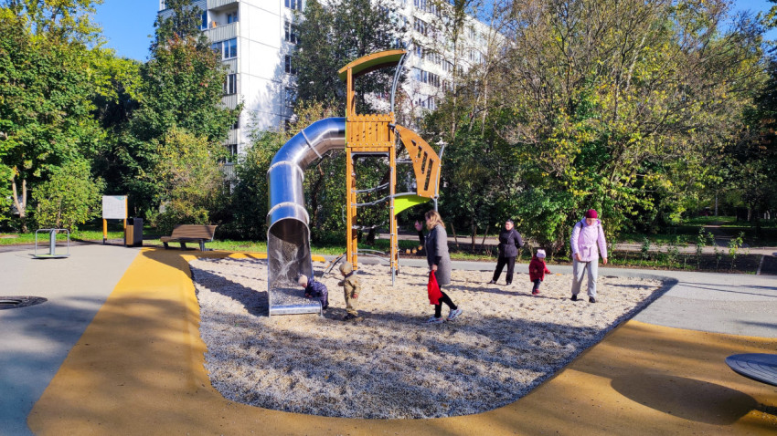 Детская площадка с металлической горкой и играющими детьми