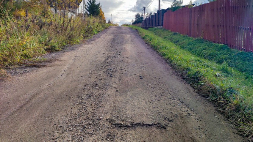 Поверхность щебёночной дороги с выбоинами и следами шин