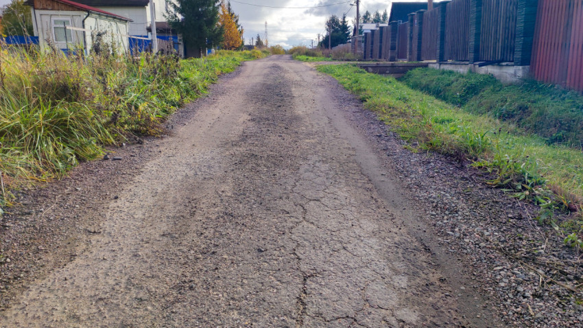 Разрушенный участок старого асфальтового покрытия на сельской улице