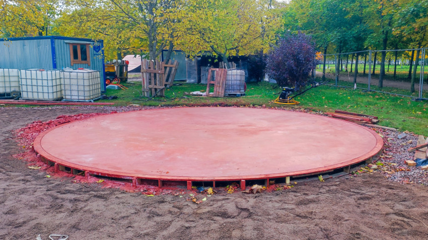 Круглая бетонная площадка на этапе строительства в парковой зоне