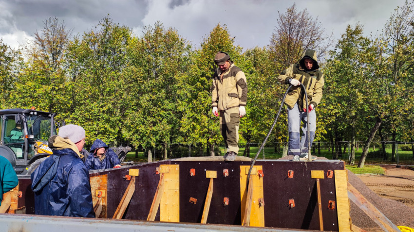 Рабочие выполняют бетонирование в опалубке на строительной площадке