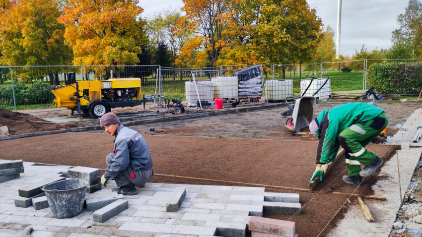 Рабочие укладывают тротуарную плитку на строительной площадке