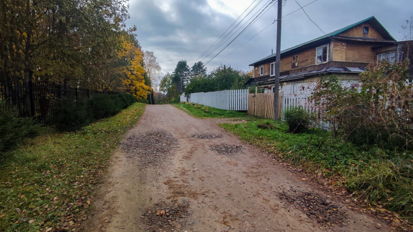 Деревенская улица с деревянными домами и грунтовой дорогой