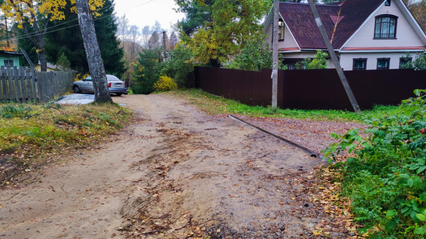 Песчаная дорога с частными домами и автомобилями