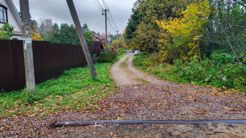 Просёлочная дорога с опорой электросети и забором