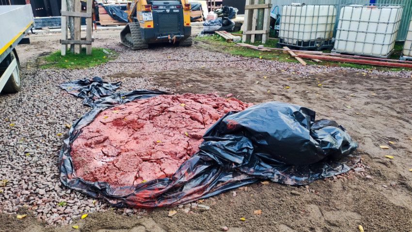 Красная строительная смесь на площадке возле техники