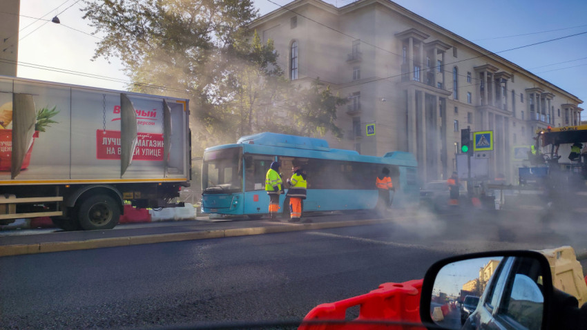 Рабочие на дорожном ремонте возле автобуса и асфальтоукладчика