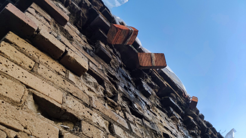 Разрушенная кирпичная кладка с красными кирпичами и следами влаги