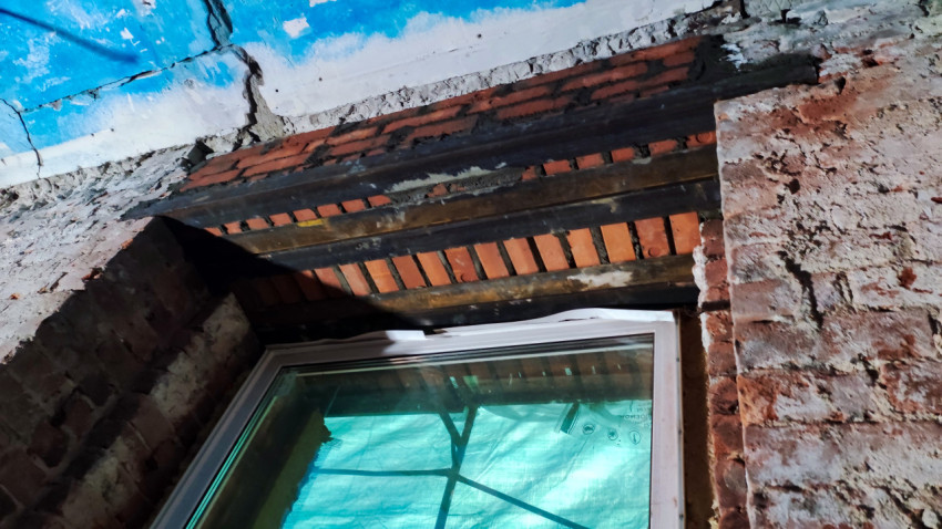 Металлические балки над оконным проёмом кирпичного здания