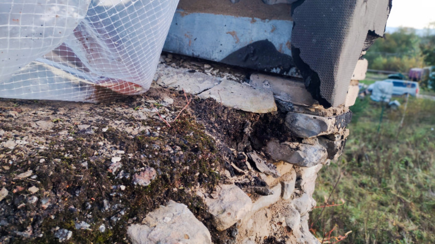 Повреждённая кирпичная стена с трещинами и укрытием из плёнки