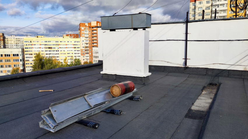 Кровля жилого дома с вентиляционной шахтой и строительными материалами