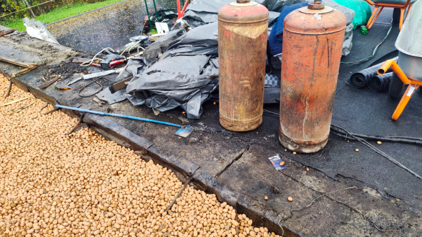 Газовые баллоны и рабочие материалы на кровле при ремонте покрытия