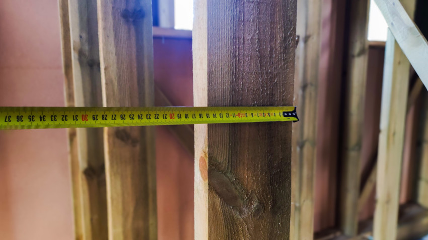 Измерение расстояния между стойками каркасной стены рулеткой