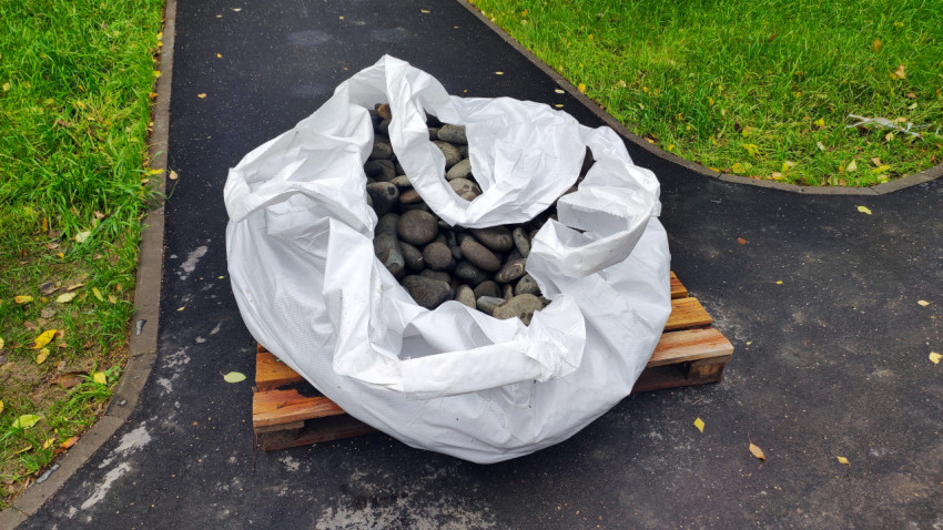 Мешок с камнями на деревянном поддоне на асфальтовой дорожке