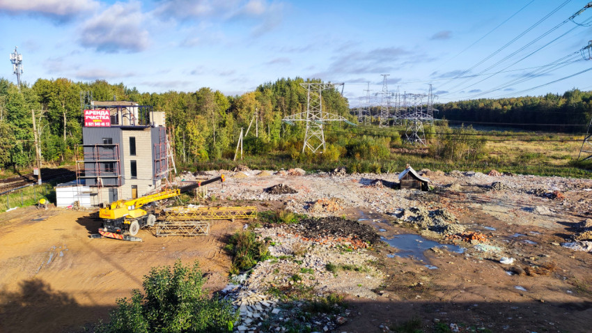 Недостроенное здание и строительная техника на фоне леса