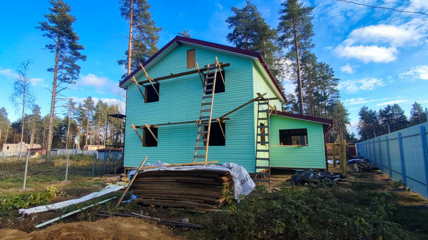 Дом в процессе отделки фасада с приставной лестницей