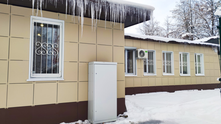 Здание с металлическими решётками на окнах и сосульками на крыше зимой